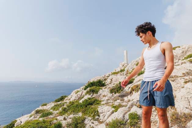 Creative Highlight Symbolbilder A teen boy stands at top of mountain peak looking over sea in summer Marseille, Provence-Alpes-Côte d Azur, France CR_RETI250919-1826463-01 ,model released, Symbolfoto