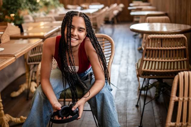 Creative Highlight Symbolbilder girl with afro-braids sits at a table in a cafe with headphones on. Saint Petersburg, Saint Petersburg, Russia CR_YFCG250918-1842817-01 ,model released, Symbolfoto