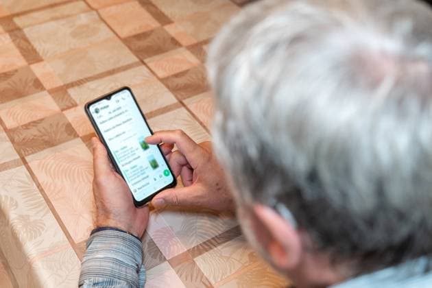 Germany - September 21, 2025: An elderly man sits at a table and types a message on WhatsApp on his smartphone. The image shows digital communication among seniors and everyday exchanges using modern technology. *** Ein älterer Mann sitzt am Tisch und tippt auf seinem Smartphone eine Nachricht bei WhatsApp. Das Bild zeigt die digitale Kommunikation von Senioren und den alltäglichen Austausch über moderne Technik.