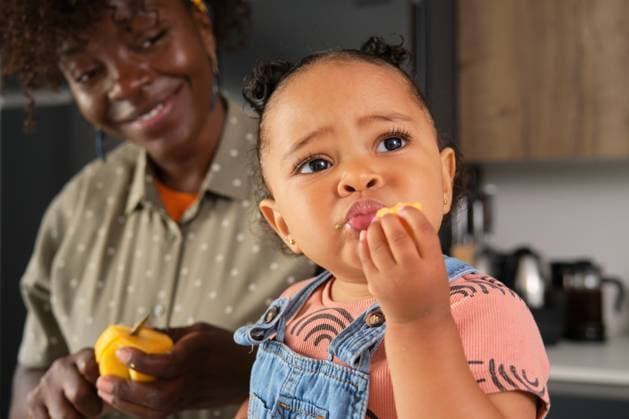 Toddler eating peach snack with mother at home kitchen model released, Symbolfoto property released, CVMF00115