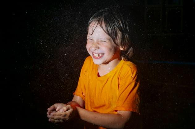IMAGO Creative, Jahreszeit Sommer, Regen, Sommerregen Smiling child in orange shirt playing in rain at night model released, Symbolfoto, ANAF05001