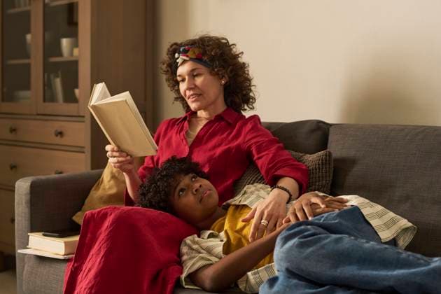 Mother reading a book to son at home relaxing on the sofa model released, Symbolfoto property released, DSHF02697