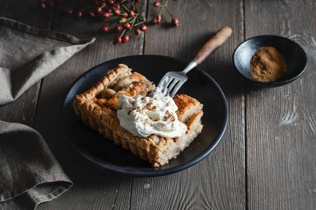 Apple pie slice with cream on plate on wooden table in studio, EVGF04533