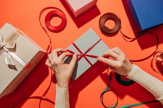Woman wrapping Christmas presents with ribbon on red festive table model released, Symbolfoto, VSNF04075