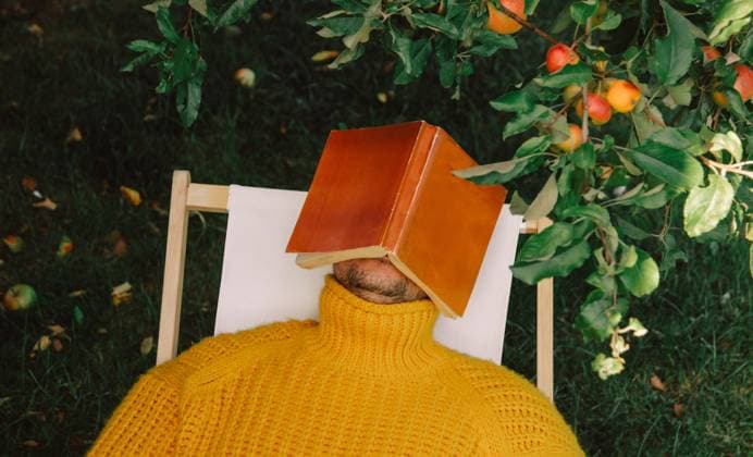 Person resting under apple tree with book on head in autumn garden model released, Symbolfoto, VSNF04086