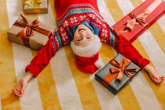 Child in Christmas hat smiling with gifts on carpet indoors model released, Symbolfoto, VSNF04115
