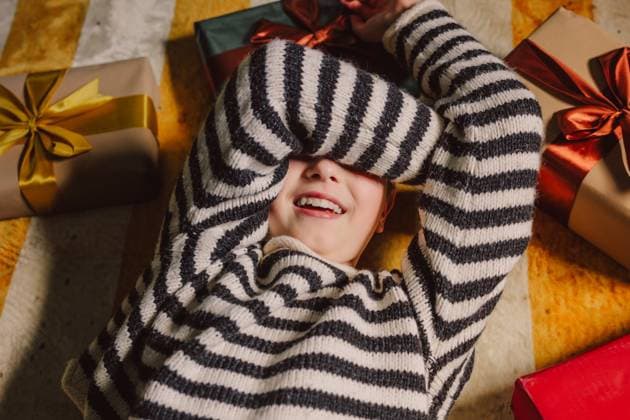Happy child in striped sweater with Christmas gifts lying on carpet indoors model released, Symbolfoto, VSNF04119