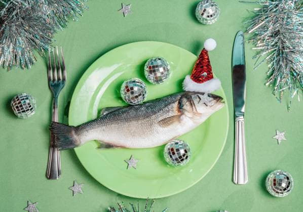 Raw fish on plate with Santa hat and festive party decorations, AAF00246