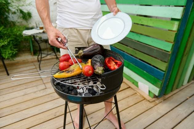 Man grilling vegetables on a backyard BBQ grill, preparing a healthy and delicious outdoor meal A man grilling assorted vegetables, including tomatoes, eggplant, and bell peppers, on a backyard BBQ. The scene captures a healthy and delicious outdoor meal preparation., model released, , property released, , 61018526.jpg RECORD DATE NOT STATED
