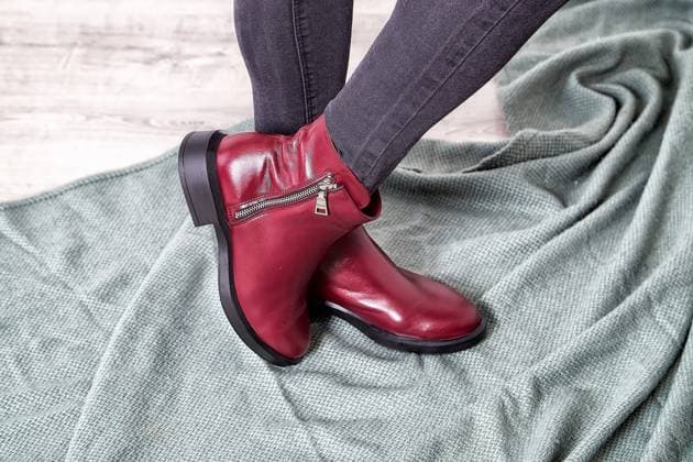 Trendy model showcasing stylish burgundy ankle boots on soft fabric backdrop while posing at indoor setting Model exhibits chic burgundy ankle boots while striking a pose on a textured surface, capturing modern fashion essence indoors., 94346588.jpg RECORD DATE NOT STATED