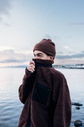 Creative Highlight Symbolbilder MR_ID30864_22683_NicolasMortarini.jpg Bundled in a warm brown jacket and beanie, a person stands by a tranquil lake in Patagonia, Ushuaia. The serene scene captures the chilly, peaceful atmosphere Model Released NicoMortarini_ID30864_1046310_025 Copyright: xNicoxMortarinix