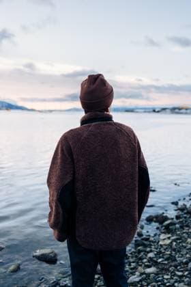 MR_ID30864_22683_NicolasMortarini.jpg A person stands by the rocky coast of Ushuaia, gazing across the tranquil Patagonian waters under a serene sky, dressed warmly in a brown jacket and beanie Model Released NicoMortarini_ID30864_1046308_023 Copyright: xNicoxMortarinix