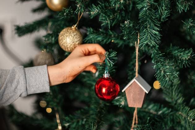 A child places a shiny red ornament on a beautifully decorated Christmas tree, adorned with golden baubles and festive decorations, capturing the holiday spirit. Model Released Selena3726_ID31433_1068904_003 Copyright: xSelena3726x RECORD DATE NOT STATED