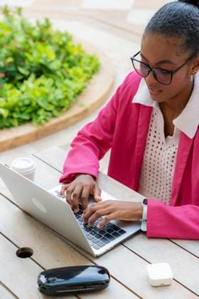 MR_ID31069_22423_WendyMedinaContreras.jpg A professional black businesswoman working on a laptop outdoors in Cartagena de Indias, Colombia. She is dressed in a pink outfit, focused on her tasks Model Released VictorCuenca_ID31069_1053942_027 Copyright: xVictorxCuencax