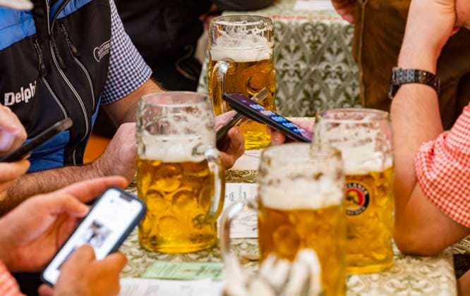 Besucher der Wiesn schauen im festzelt auf ihre Handys vor ihnen die erste Mass Bier am Morgen kurz nach Eröffnung des Oktoberfestes bei verregnetem Wetter Wolken Regen Schlechtwetter auf der Wiesn Oktoberfest in München Datum: 30.09.2025 *** Visitors of the Oktoberfest looking at their cell phones in the tent in front of them the first mass of beer in the morning shortly after the opening of the Oktoberfest in rainy weather clouds rain bad weather at the Oktoberfest Oktoberfest in Munich Date 30 09 2025