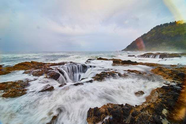 Creative Highlights World Thor s Well Rock Formations with Cascading Waterfalls Eye-Level Perspective Witness the raw power and beauty of Thor s Well in Yachats, Oregon as waves crash over rugged rocks under a soft rainbow, capturing the essence of nature s relentless energy and tranquil coastal charm., 60920536.jpg RECORD DATE NOT STATED
