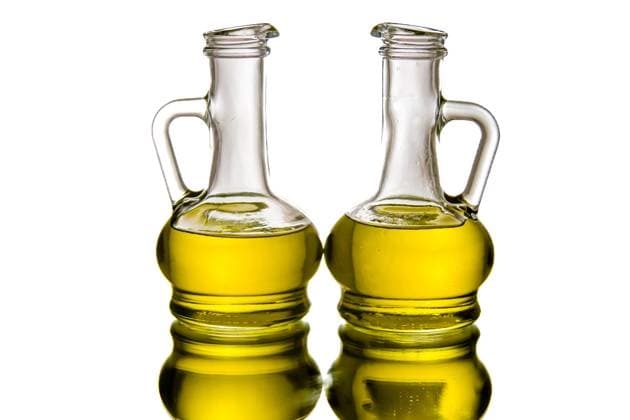 Two glass bottles filled with olive oil, placed side by side on a reflective surface, against white background and studio light. Two glass bottles filled with olive oil, placed side by side on a reflective surface, against white background and studio light., 60934994.jpg RECORD DATE NOT STATED