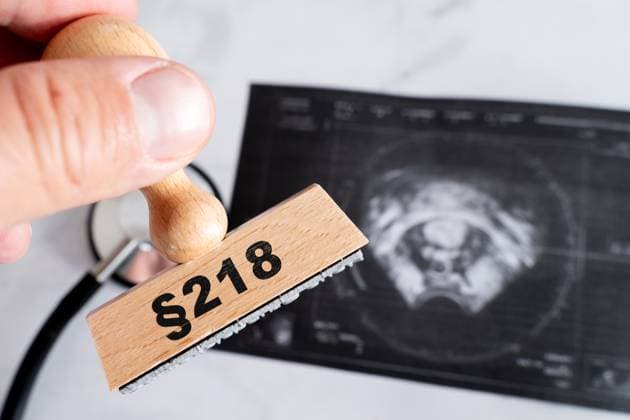 Bavaria, Germany - October 3, 2025: PHOTOMONTAGE, symbolic photo on the subject of abortion with wooden stamp Âß218 in front of an ultrasound image. Depiction of the legal and medical tensions surrounding abortion in Germany *** FOTOMONTAGE, Symbolfoto zum Thema Schwangerschaftsabbruch mit Holzstempel Âß218 vor einem Ultraschallbild. Darstellung des rechtlichen und medizinischen Spannungsfeldes rund um Abtreibung in Deutschland