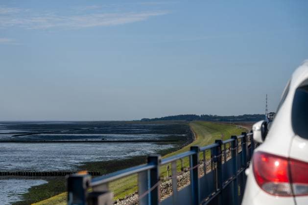 Reise auf die Insel Sylt. Blick vom Autotransportwagen auf den Hindenburgdamm in Richtung der Insel Sylt in einer Linkskurve bei Ebbe. Am rechten Rand angeschnitten ein PKW. Nordfriesland Schleswig-Holstein Deutschland *** Journey to the island of Sylt View from the car transporter on the Hindenburgdamm in the direction of the island of Sylt in a left-hand bend at low tide A car cut off on the right-hand edge Nordfriesland Schleswig Holstein Germany