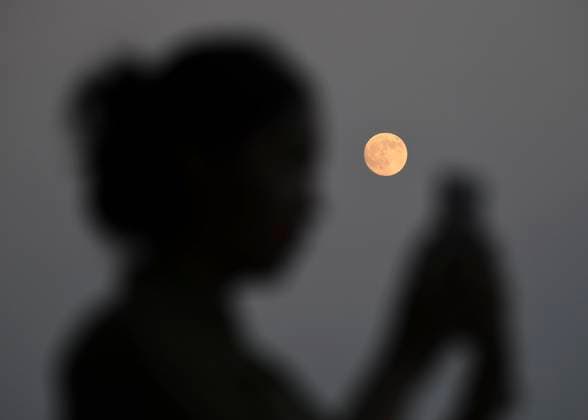 (251006) -- BEIJING, Oct. 6, 2025 -- A tourist checks photos of the full moon near the West Lake in Hangzhou, east China s Zhejiang Province, Oct. 6, 2025. Monday marks this year s Mid-Autumn Festival, which is celebrated annually on the 15th day of the eighth month in the Chinese lunar calendar. People across China admire the full moon to celebrate the traditional holiday. (Photo by Xinhua) CHINA-MID-AUTUMN FESTIVAL-MOON (CN) LongxWei 