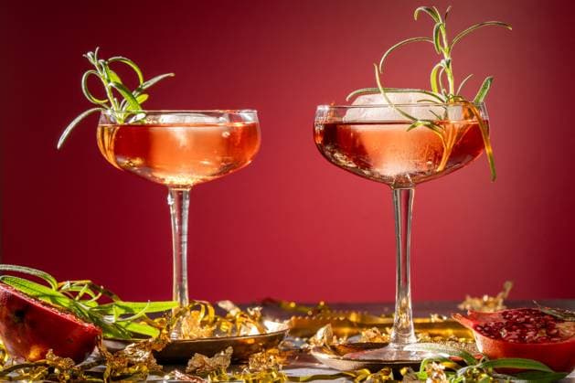 two red cocktails with a rosemary garnish with gold shot in a studio Norrtälje, Stockholm County, Sweden CR_RABE251007CB-1843408-01