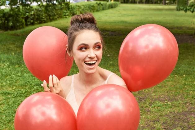 Junge kaukasische erwachsene Frau lächelnd umgeben von roten Luftballons in grün Young caucasian adult female smiling surrounded by red balloons in green outdoor park setting. (License=RF) ,model released, Symbolfoto Copyright: xZoonar.com ElenaxSafonovax 24031544 ,model released, Symbolfoto ,property released