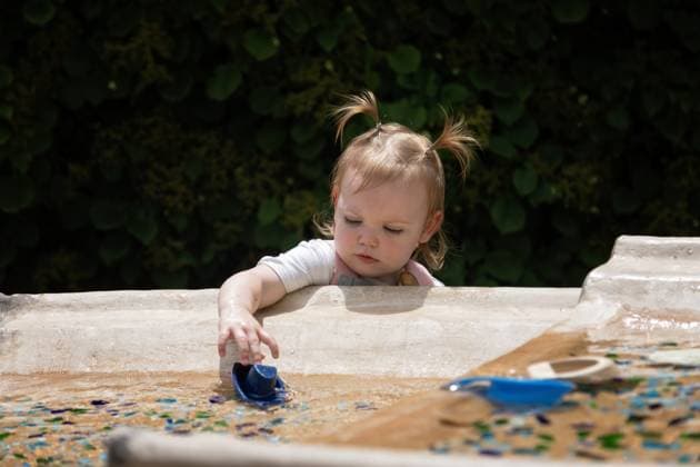 Cute little girl in pigtails plays with toy boat in water on sunny day St. Louis, Missouri, United States R_CYVA251009-1861367-01 ,model released, Symbolfoto