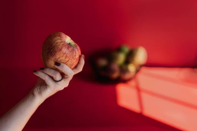Woman?s Hand Holding Red Apple on Red Background Tulsa, Oklahoma, United States R_KRRY251009-1849479-01