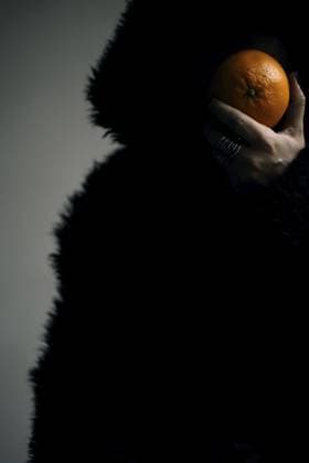 Porträt einer Frau in einer schwarzen Felljacke mit einer Orange in der Hand Portrait of a woman in a black fur jacket with an orange in her hand Copyright: imageBROKER FranziskaxRitter ibxadr15325930.jpg ,model released, Symbolfoto ,property released