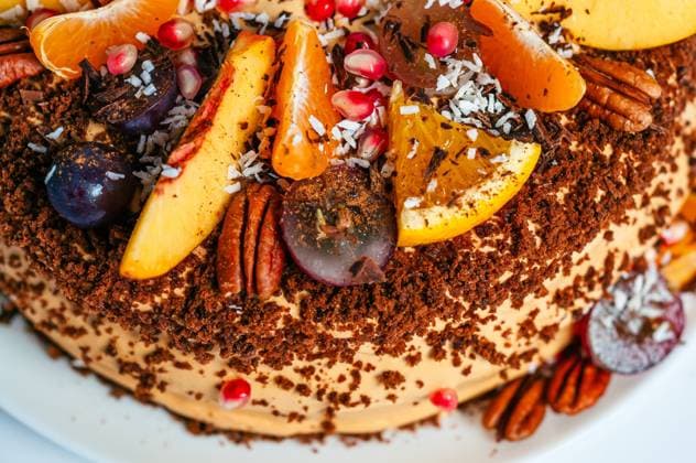 Nahaufnahme eines köstlichen Obstkuchens mit frischen Orangen, Weintrauben und Pekannüssen, perfekt für eine Feier. A beautifully decorated cake with an assortment of fresh fruits, including oranges, grapes, and peaches. The cake is topped with nuts and coconut flakes. (License=RF) Copyright: xZoonar.com AndriixAbryutinx 24046096
