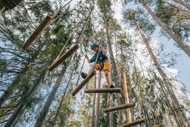 Boy crossing swinging log bridge in forest high ropes, safety harness Saint Petersburg, Saint Petersburg, Russia CR_KSLI25101315-1833932-01 ,model released, Symbolfoto
