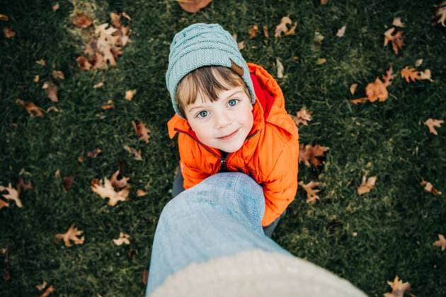 Child in orange coat hugs leg, looking up with a sweet smile North Andover, Massachusetts, United States CR_FKNH251013B-1850437-01 ,model released, Symbolfoto