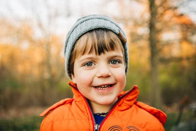 Smiling child in orange coat and gray beanie during golden hour North Andover, Massachusetts, United States CR_FKNH251013B-1850454-01 ,model released, Symbolfoto