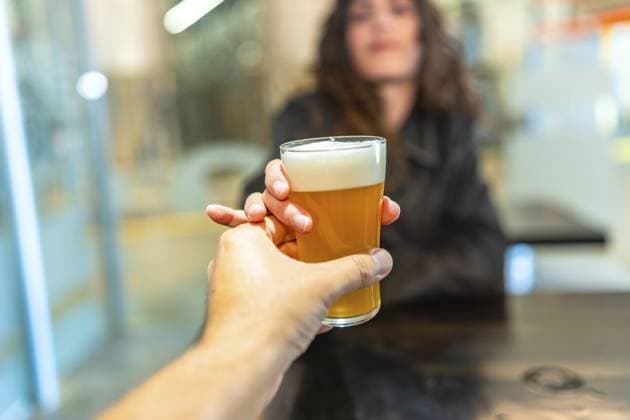 Ein erfrischendes Glas Craft Bier in der Hand, das er einer Frau in einer Bar überreicht, steht für Verkostungen, Brauereibesuche, geselliges Beisammensein und den Genuss von Getränken Hand holding a refreshing glass of craft beer, presenting it to a woman in a bar, representing tasting, brewery visits, social gatherings, and enjoying drinks Copyright: imageBROKER UnaixHuizi ibxuhu15266252.jpg ,model released, Symbolfoto ,property released