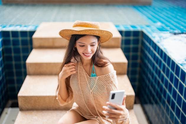 Junge hispanische Frau der Generation Z nutzt ihr Smartphone, um während des Sommerurlaubs am Pool des Resorts ihre sozialen Medien zu aktualisieren. Young Hispanic Gen Z Woman Using Smartphone to Update Social Media by Resort Pool During Summer Vacation (License=RF) ,model released, Symbolfoto Copyright: xZoonar.com SirijitxJongcharoenkulchaix 23929251 ,model released, Symbolfoto ,property released