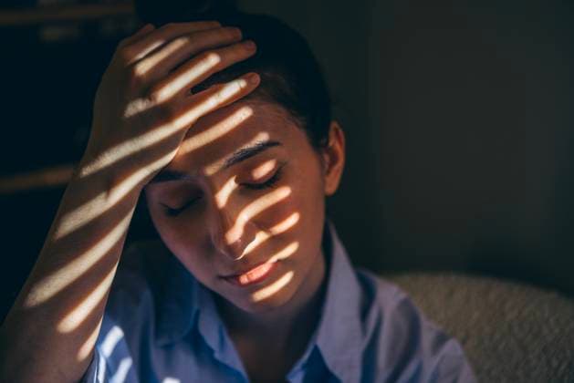 Porträt einer jungen, müden Frau in einem blauen Hemd, die auf einem Stuhl sitzt. Das Mädchen mit Kopfschmerzen Portrait of a young tired woman in a blue shirt sitting on a chair. The girl with a headache has closed her eyes and is holding her head with her hand. The student is suffering from a migraine at home (License=RF) ,model released, Symbolfoto Copyright: xZoonar.com DashaxPetrenkox 23944739 ,model released, Symbolfoto ,property released