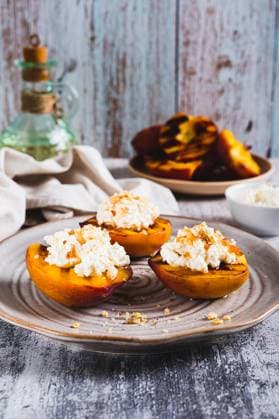 Gegrillte Pfirsichhälften mit Ricotta und Nüssen auf einem Teller auf dem Tisch Vertikalansicht Gegrillte Pfirsichhälften mit Ricotta und Nüssen auf einem Teller auf dem Tisch Vertikalansicht (License=RF) Copyright: xZoonar.com ElenaxRuix 23934224