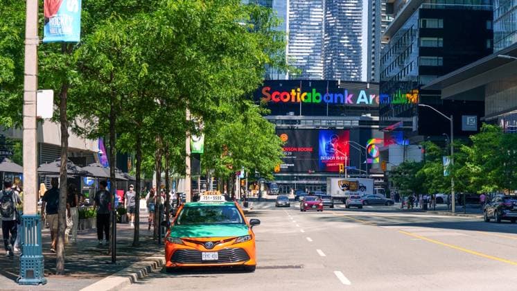 Scotiabank Arena in Toronto mit lebhafter Beschilderung, belebter Straßenszene und einem geparkten orangefarbenen Taxi, das das städtische Leben und die Unterhaltungskultur in Kanada zeigt Toronto ON, Canada - June 29, 2025: Scotiabank Arena in Toronto features bright signage, busy street with pedestrians, and an orange taxi parked nearby, capturing the lively atmosphere (License=RM) Copyright: xZoonar.com IuliiaxDombrovskaiax 23948462