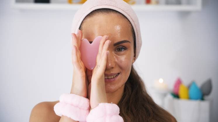 Eine Beauty-Bloggerin hält Gua Sha in der Nähe ihres Gesichts und bedeckt damit ein Auge A beauty blogger girl holds a Gua Sha tool near her face, playfully covering one eye with it, highlighting her skincare routine in a stylish and engaging manner (License=RF) ,model released, Symbolfoto Copyright: xZoonar.com AndreiixMoiseix 23935055 ,model released, Symbolfoto ,property released