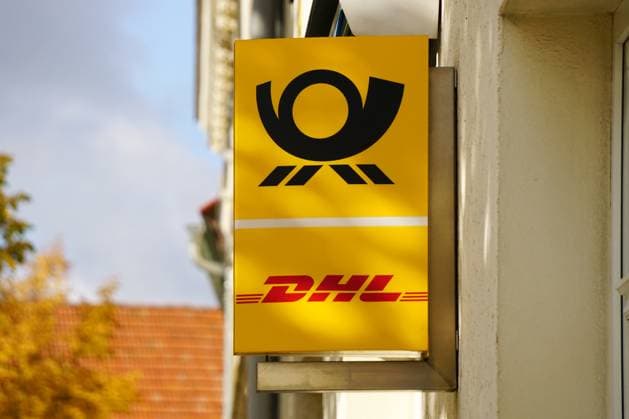 Paketannahme, DHL Reklameschild mit Postsymbol am Eingang einer Postfiliale *** Parcel acceptance, DHL Advertising sign with Post symbol on Entrance a Postal branch 1131606006