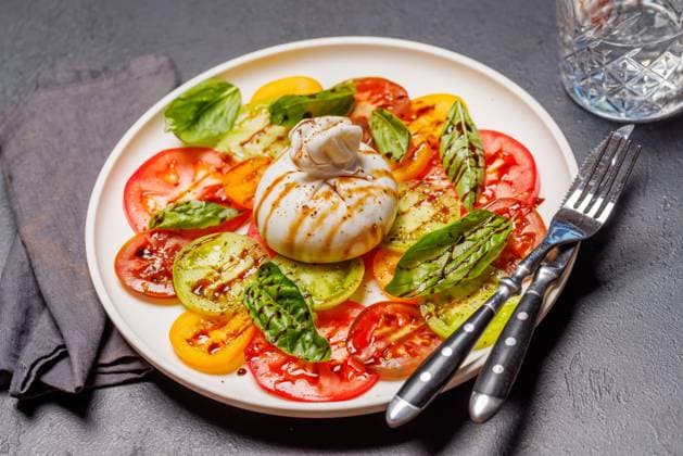 Frische Burrata, serviert auf bunten Tomatenscheiben Fresh burrata served on slices of colorful tomatoes, drizzled with olive oil and herbs (License=RF) Copyright: xZoonar.com EvgenyxKarandaevx 24080846