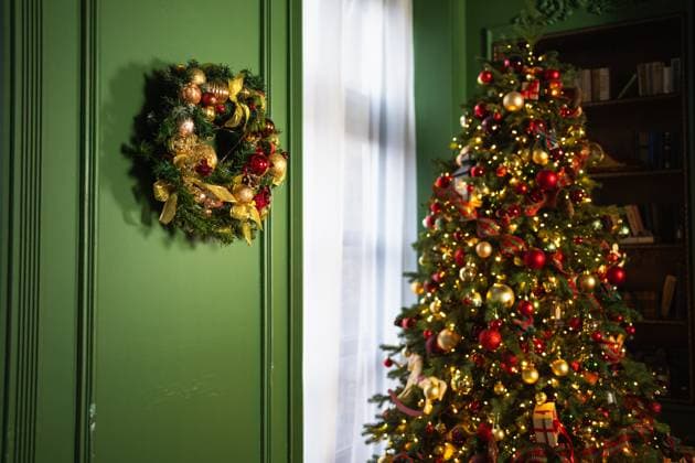 Idee für Weihnachtsdekoration. Haus für die Feiertage dekoriert. Weihnachtskranz Girlande auf grüne Wand und Weihnachtsbaum mit goldenen roten Ornamenten Dekoration Spielzeug und Girlande Lichter im Wohnzimmer. Christmas decoration idea. House decorated for holidays. Christmas wreath garland on green wall and Christmas tree with golden red ornaments decoration toys and garland lights in living room (License=RF) Copyright: xZoonar.com IuliiaxZavalishinax 24081349