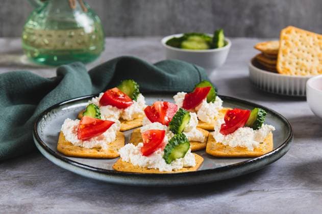 Vorspeise aus Crackern mit Ricotta, Gurke und Tomate auf einem Teller auf einem Tisch Appetizer of crackers with ricotta, cucumber and tomato on a plate on a table (License=RF) Copyright: xZoonar.com ElenaxRuix 24081956