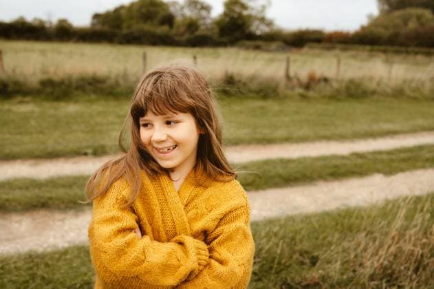 Child girl smiling outdoors in a yellow knitted sweater. Corby, England, United Kingdom CR_JNDO251020-1868294-01 ,model released, Symbolfoto