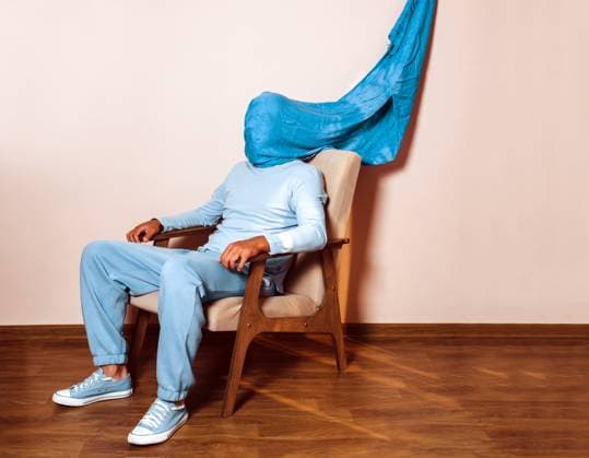 Man dressed in blue with covered head expressing sadness in armchair model released, Symbolfoto, AAF00209