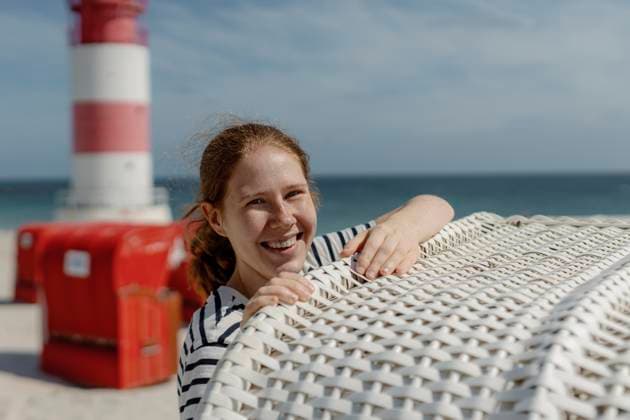 Smiling redhead at North Sea beach by lighthouse on Helgoland - Düne model released, Symbolfoto, MCHF00602