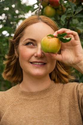 Woman in a garden holding an apple near the eye during autumn harvest model released, Symbolfoto property released, IGEF00066