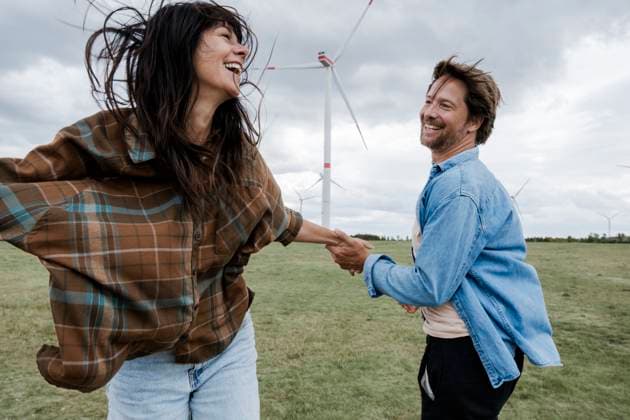 Couple holding hands and laughing outdoors near wind turbines model released, Symbolfoto, KNSF11848