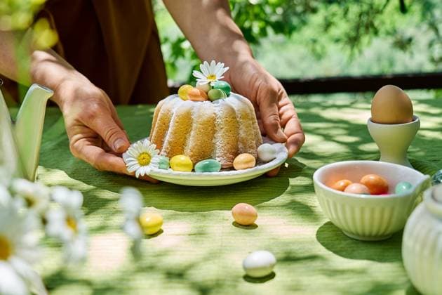 Woman decorating sponge cake with easter eggs and daisies outdoors model released, Symbolfoto, CATF00807