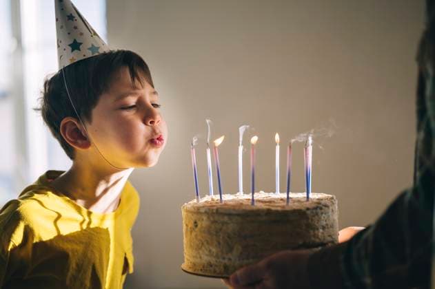 Child blowing out birthday cake candles at a joyful family celebration model released, Symbolfoto property released, ANAF05221